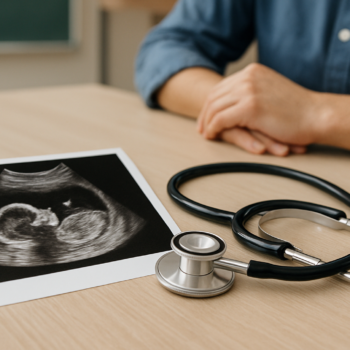 Ultrasound image of a fetus next to a stethoscope on a wooden table