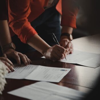 Someone signing legal documents on a wooden table