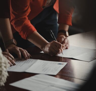 Someone signing legal documents on a wooden table