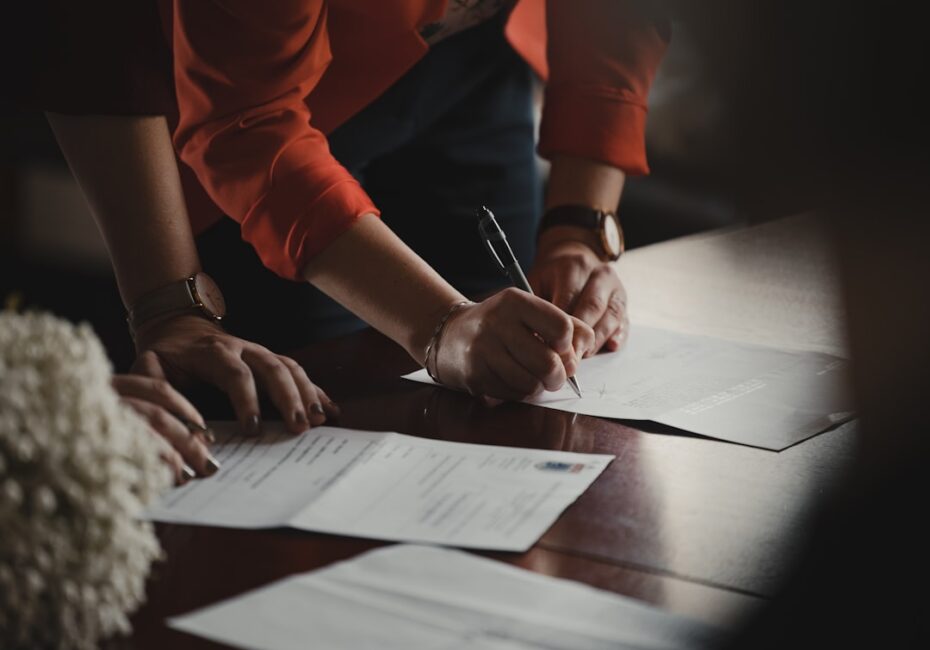 Someone signing legal documents on a wooden table